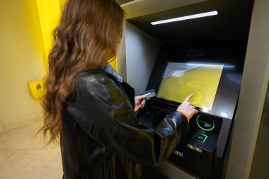 Genç esmer kız sarı ATM 'de kredi kartından para çekiyor..