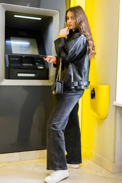 Young Thoughtful Brunette Girl Withdrawing Money Credit Card Yellow Atm — Stock Photo, Image