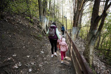 Anasının sırtı ve küçük çocukları bahar doğasında doğa yürüyüşü yapıyor..