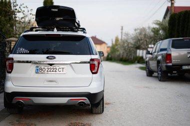 Ternopil, Ukrayna - Mayıs 2023: Ford Explorer aile arabası çatı rafı Thule Motion XXL kutusu Ukrayna plakalı.