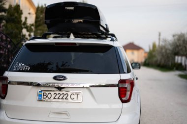 Ternopil, Ukrayna - Mayıs 2023: Ford Explorer aile arabası çatı rafı Thule Motion XXL kutusu Ukrayna plakalı.