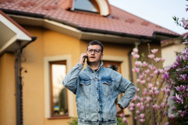 Gözlüklü ve kot ceketli şık bir adamın portresi, evine cep telefonuyla poz vermiş..