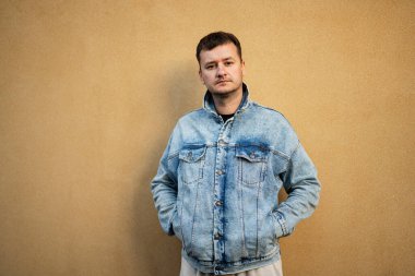 Sarı duvara karşı kot ceketli şık bir adamın portresi..