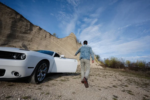 ジーンズのジャケットを着た男の背中とキャリアの中で彼の白い筋肉車のキャップオープンドア ロサンゼルス — ストック写真