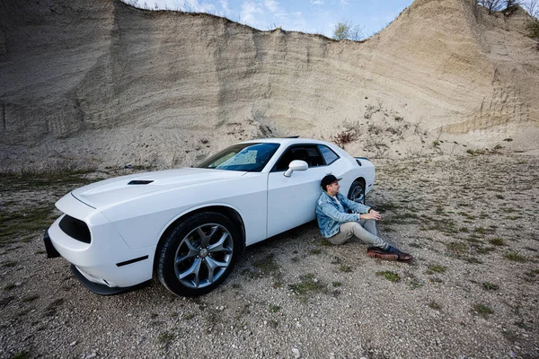 Przystojny Mężczyzna Jeansowej Kurtce Czapce Siedzi Pobliżu Swojego Białego Samochodu — Zdjęcie stockowe