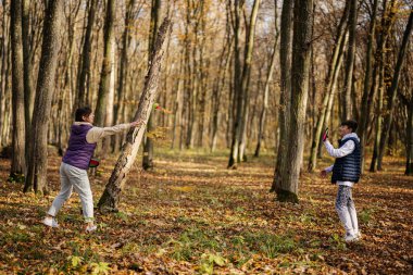 Anne ve oğlu sonbahar ormanlarında oynuyorlar. Yakala ve top oyna..