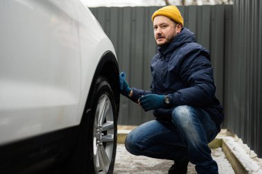 Man wipes american SUV car with a microfiber cloth after washing in cold weather.