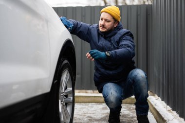 Man wipes american SUV car with a microfiber cloth after washing in cold weather.