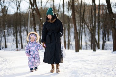 Mother and child walking on a sunny frosty winter day in the park.