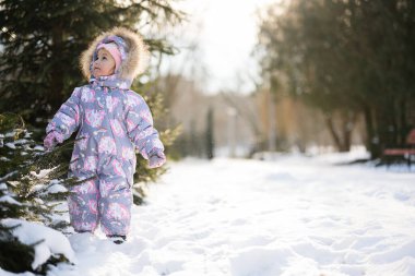 Baby girl wear child snowsuit on a sunny frosty winter day.