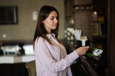 Temassız ödeme yapan genç, güzel esmer kadın, NFC teknolojisinin yanında cep telefonu tutan bayan müşteri.. 