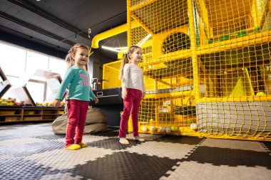 Çocuk oyun merkezinde sensör tarafından modern video oyun konsoluyla dans eden iki kız kardeş..