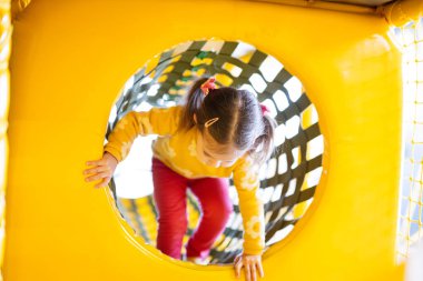 Küçük kız sarı çocuk parkındaki eğlence parkında borularla hayatına devam ediyor..