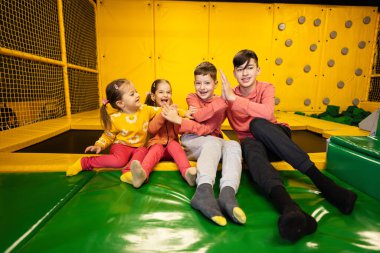 Çocuklar birlikte oyun parkında oturup beşlik çakıyorlar. Aktif eğlencelerde kardeşlerim ve kardeşlerim..