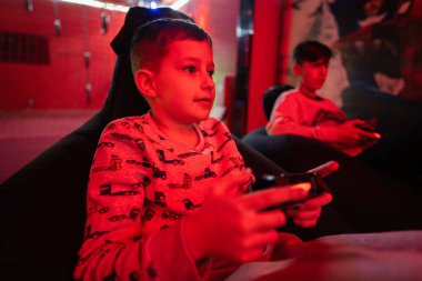 İki erkek oyuncu kırmızı oyun odasında oyun konsolu oynuyorlar..