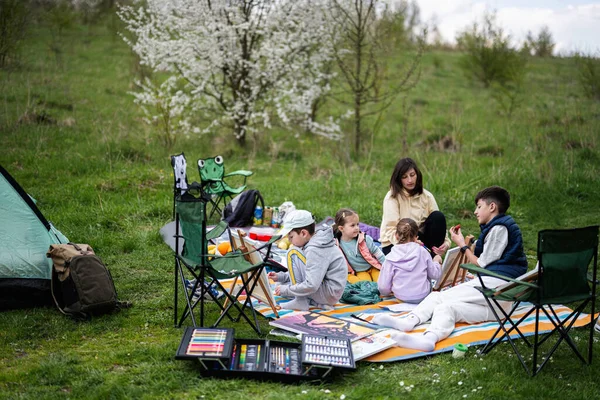 ガーデン春の公園でピクニックブランケットの絵で楽しさと屋外を楽しんでいる幸せな若い家族 母親と子供 リラクゼーション — ストック写真