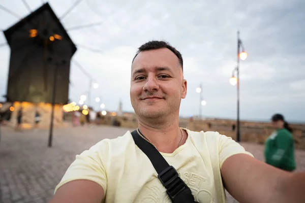 一名面带微笑的游客在保加利亚内塞巴尔磨坊附近的人行道上自拍的画像 免版税图库照片