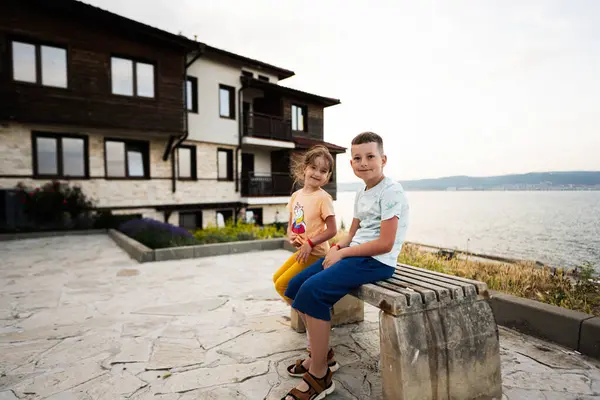 ネッセバーの海のそばの家の前のベンチに座っている男の子と女の子 — ストック写真