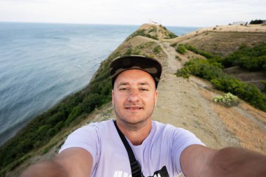 Deniz ve dağların arka planındaki bir adamın selfie 'si. Cape Emine, Karadeniz kıyısı, Bulgaristan.