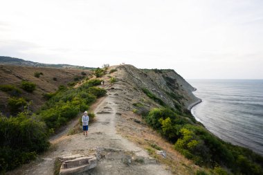 Çocuk deniz manzaralı bir uçurumda yürüyor. Cape Emine, Karadeniz kıyısı, Bulgaristan.