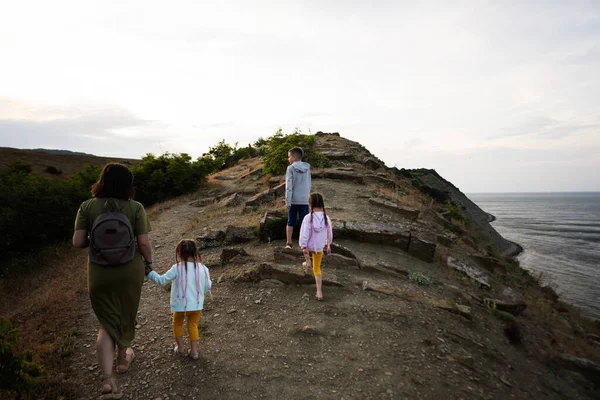 Family of mother and three kids walking on the cliff above the sea. Cape Emine, Black sea coast, Bulgaria.