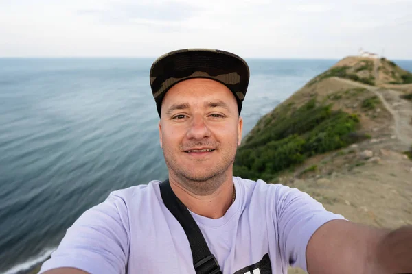 一个戴着帽子的笑脸男子在海的背景上自拍的画像 保加利亚黑海海岸埃米纳角 图库照片