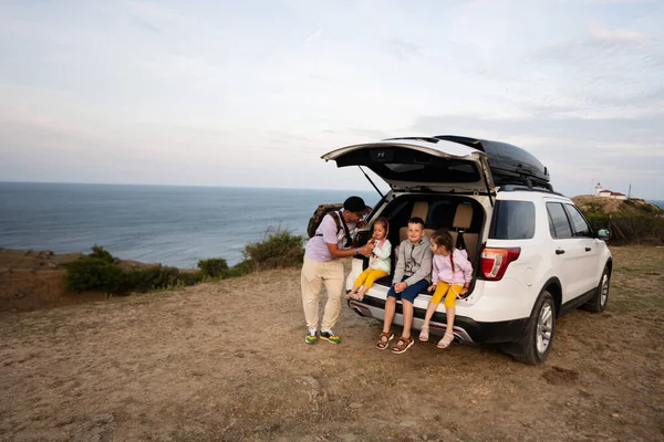 快乐的一家人坐在海滩上的一辆越野车的行李箱里 保加利亚黑海海岸埃米纳角 图库图片
