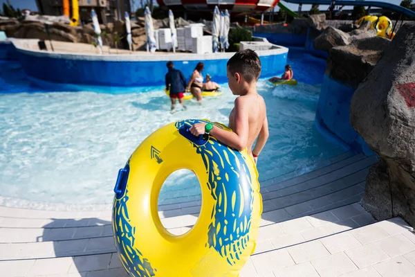 Boy with inflatable ring in swimming pool. Summer holiday concept.