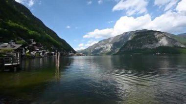 Avusturya Alpleri 'ndeki resim gibi bir göl köyü. İnsanlar güneşli bir günde güzel dağ manzaralı bir tekne gezisinden hoşlanırlar..