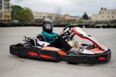 Yoğun bir yarış sırasında go-kart kullanan siyah kasklı bir çocuk. Go-kart yarışının heyecanını ve heyecanını yaşayın..