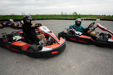Miğferli iki çocuk açık havada go-kart yarışıyor, eğlence ve heyecan yaşıyorlar..