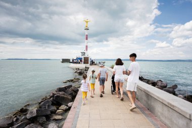 Aile deniz kenarındaki bulutlu bir günde bir deniz fenerine doğru yürüyüp sakin ve huzurlu bir yürüyüşün tadını çıkarıyor..