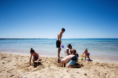 Aile sahilde güzel bir gün geçiriyor, kumdan kaleler inşa ediyor ve Hırvatistan 'ın Bilotinjak plajındaki parlak güneşin altında kumlarda oynuyor..