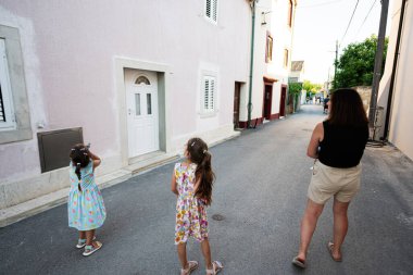 Bir anne ve iki kızı güneşli bir günde büyüleyici ve sessiz bir sokakta yürürler. Çocuklar Hırvatistan 'ın Nin kentinde meraklı ve neşeli görünüyorlar.
