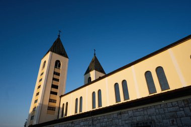 Heybetli, mavi gökyüzü altında iki çan kulesi olan Aziz James Kilisesi, Medjugorje 'deki dinsel bir yapının dinginliğini ve mimari güzelliğini yansıtıyor..