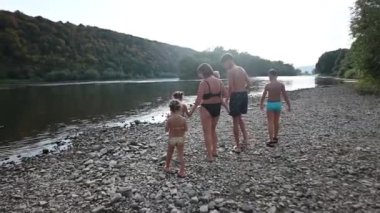 Altı kişilik bir aile, güzel bir yaz gününde kayalık bir nehir kıyısında yürür. Güneş suyun üzerinde parıldıyor. Aile birlikte vakit geçirmekten zevk alıyor..