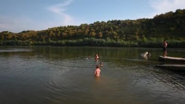 Bir grup arkadaş güneşli bir günde yüzmenin ve gölde su sıçratmanın tadını çıkarıyorlar. Yaz tatili, seyahat ve arkadaşlık kavramları için mükemmel..