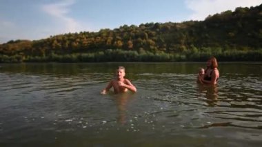 Bir aile güneşli bir günün tadını çıkarır. Yüzmek ve nehirde birlikte oynamak. Annesi bebeğini kucağında tutarken çocuk suya su sıçratıyor ve yaz neşesi ve birlikteliği için iç açıcı bir sahne oluşturuyor..