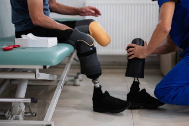 Fizyoterapist, rehabilitasyon kliniğinde uygun bir seans sırasında protez bacaklı birine yardım eder. Görüntü, tıbbi bakım ve desteğin özünü yansıtıyor..