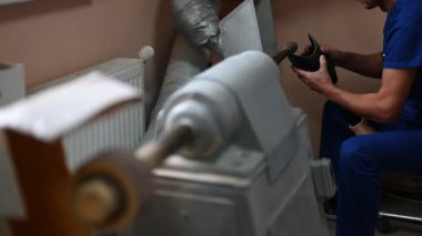 Mavi üniformalı yetenekli bir teknisyen, bir atölye ortamında ustalık ve ustalığı vurgulayan özel makineler kullanarak protez bacağını dikkatlice parlatıyor..