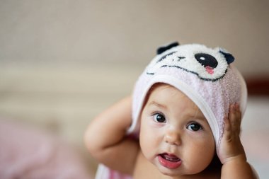 Panda temalı kukuletalı havluya sarılı şirin bir bebek. Tuhaf ve oyuncu bir ifade sergiliyor. Çocukluk, masumiyet ve şirinlik kavramları için mükemmel bir imaj..