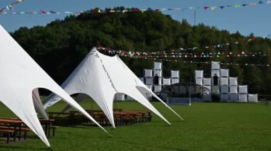 Konukların gelmesini ve bir müzik festivalinin başlamasını bekleyen beyaz çadırları ve sahneleri var..
