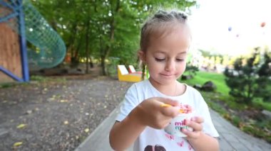 Genç bir kız güzel bir yaz gününde parkta yürürken dondurma tatlısının tadını çıkarıyor. Reklamlar, sosyal medya ve çocukluk, yaz ve tatlı ikramları ile ilgili internet siteleri için mükemmel..