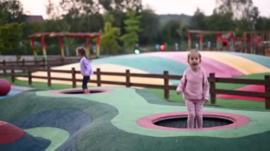 Oyun parkında trambolinde zıplayan iki küçük kız. Birlikte eğleniyorlar ve eğleniyorlar..