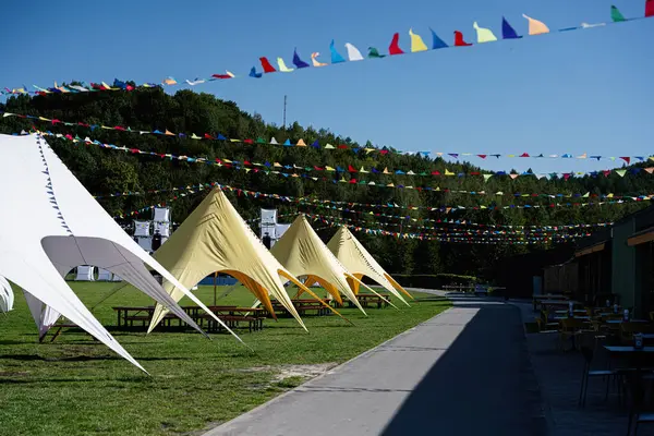 stock image Outdoor festival setup featuring colorful tents and vibrant bunting. Perfect venue for celebrations and events amidst scenic nature setting under a clear blue sky.