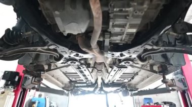 Araba tamirhanesinde hidrolik asansörle kaldırılan arabanın alt tarafı. Otomotiv, onarım ve bakım projeleri için mükemmel.