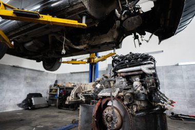 Otomobil tamirhanesindeki bir arabanın ayrıntılı görüntüsü ve şasisi. Sahne, profesyonel araç bakım ve mekanik uzmanlığın özünü yakalıyor..