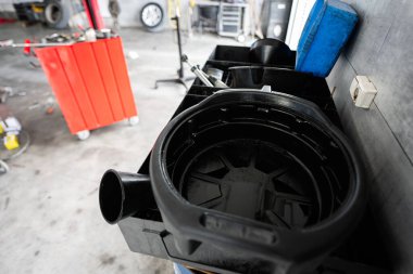 İçinde siyah yağ toplama tavası, kırmızı alet çantası ve çeşitli aletlerin bulunduğu bir otomotiv garajı. Mekanik, onarım ve araç bakımı kavramları için ideal.
