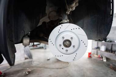 Profesyonel bir oto tamirhanesinde yeni takılmış bir araba fren diskinin ayrıntılı görünümü, otomotiv bakımı ve mekanik hassasiyeti vurgulanıyor.