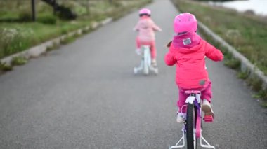 İki küçük kız nehir kenarında bisikletlerine biniyor. Çocukluk, aile, eğlence ve aktif yaşam tarzı..